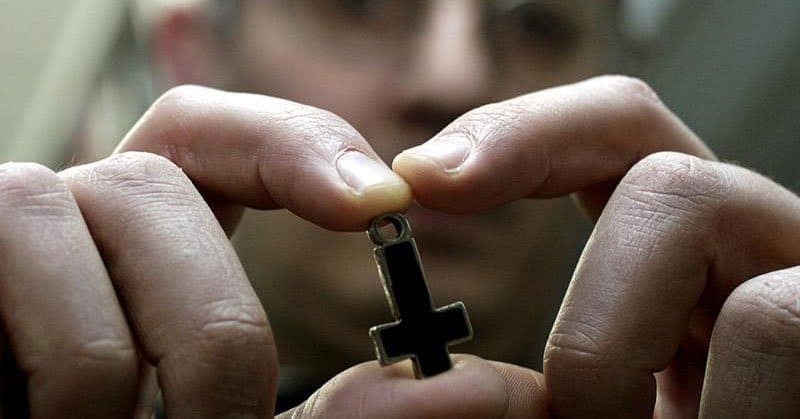 Sacerdote stringe tra le mani un crocefisso