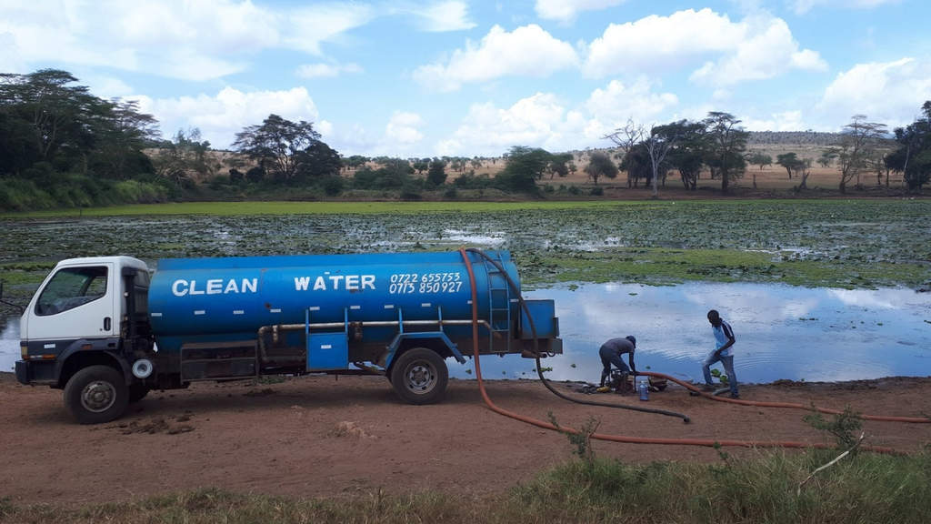 Camion blu con il quale viene riempita una pozza d'acqua