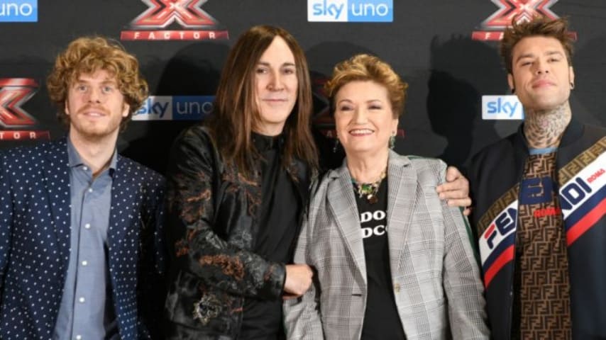 I giudici di X Factor 2018  sorridono in posa davanti ai loghi sky