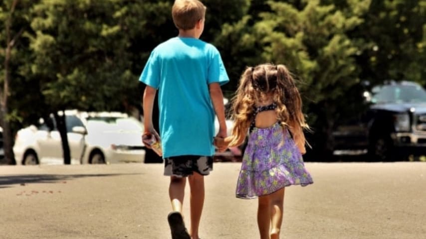 due bambini di spalle che passeggiano mano nella mano