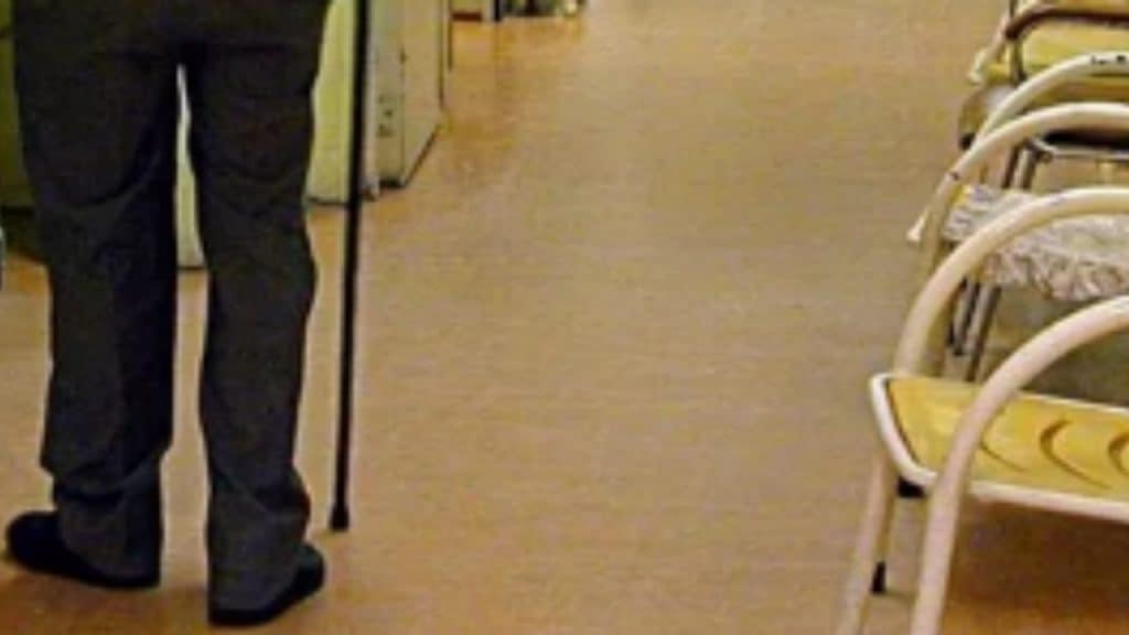 gambe di un anziano con il bastone mentre passeggia in ospedale