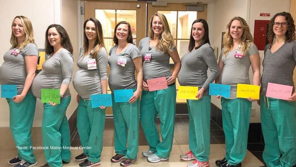 9 infermiere in fila tutte mentre mostrano il loro pancione