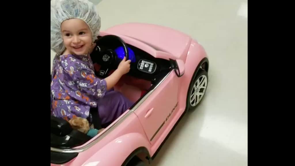 Una bimba prova felice la sua mini car rosa per andare in sala operatoria