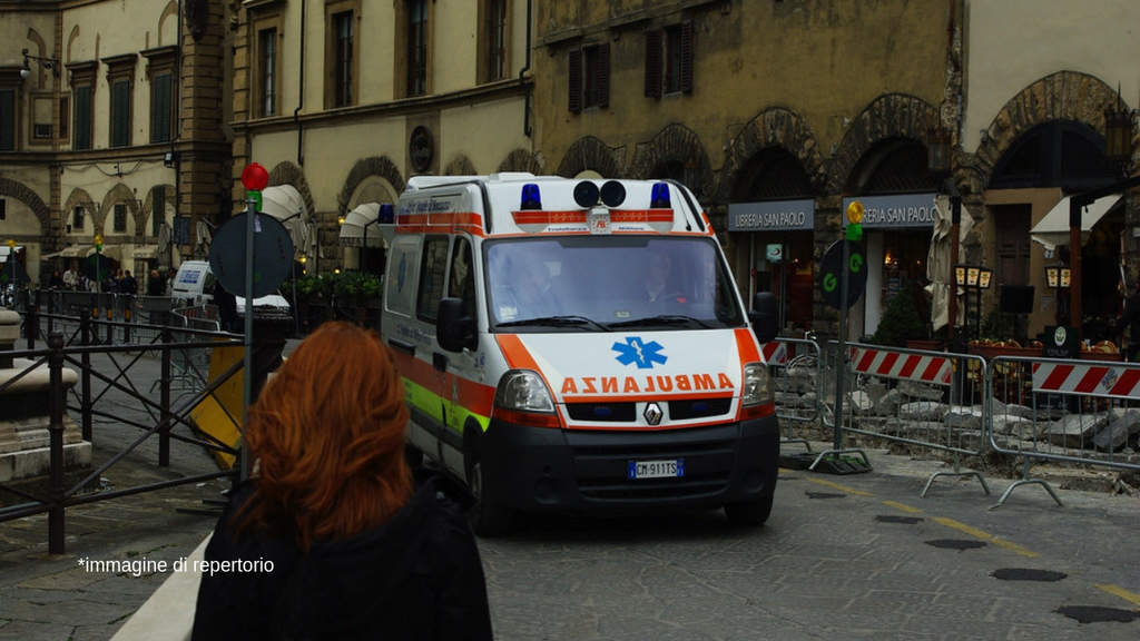 ambulanza in strada di fronte ad una donna di spalle con i capelli rossi