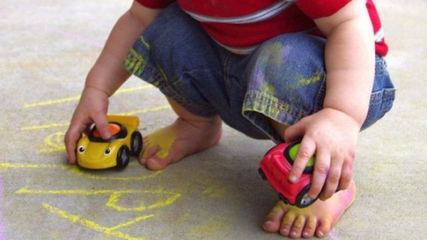 bambino mentre gioca con due macchinine