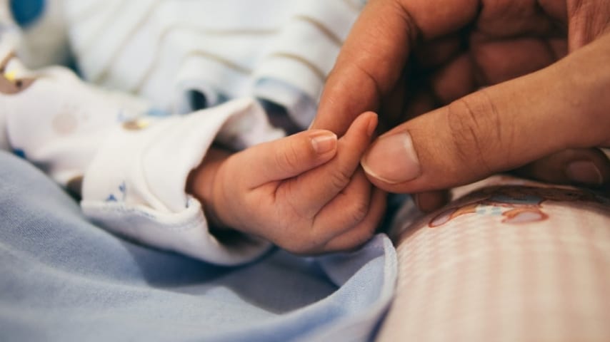 Mano della mamma che tiene la mano del proprio bimbo appena nato