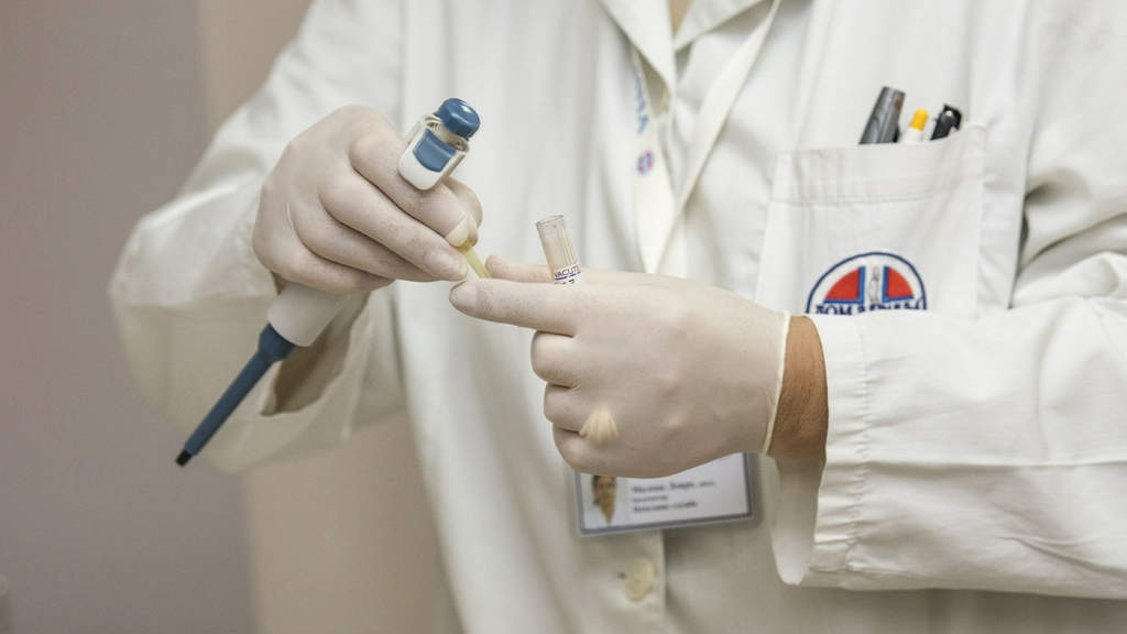 mani di un medico con i guanti e una provetta