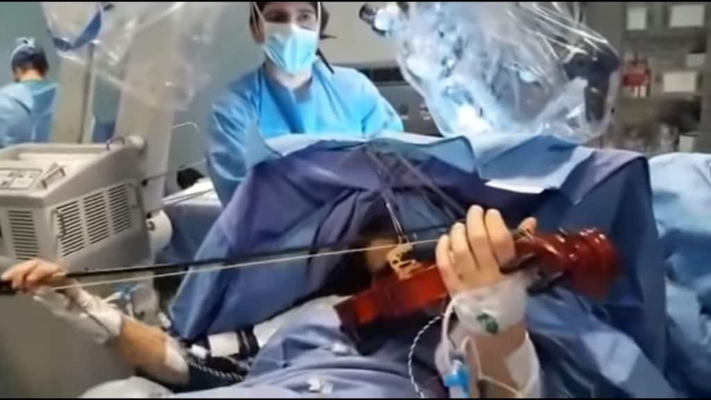 medici mentre operano una ragazza sveglia che suona il violino