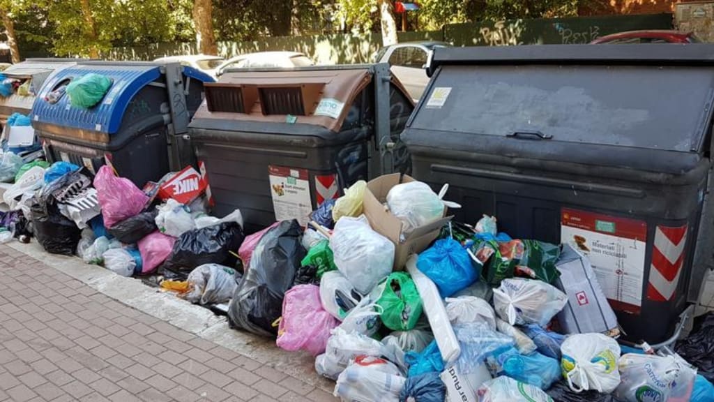 sacchetti della spazzatura sovrastano i bidoni dell'immondizia