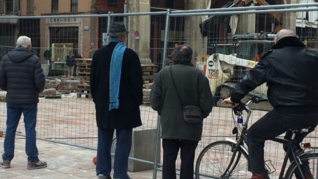 Quattro anziani guardano un cantiere urbano