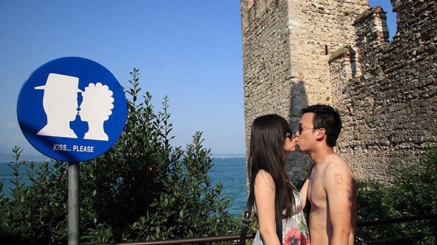 Cartello stradale per "obbligo di bacio" e coppia che si bacia 