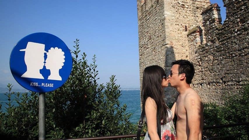 Cartello stradale per "obbligo di bacio" e coppia che si bacia