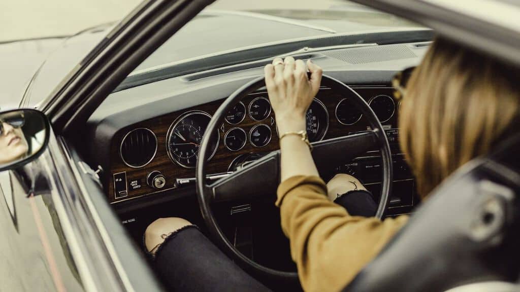 mani di donna al volante inquadrate da dietro