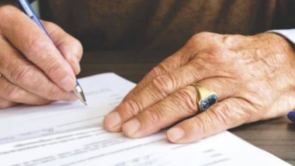 mani di un anziano che firma un documento