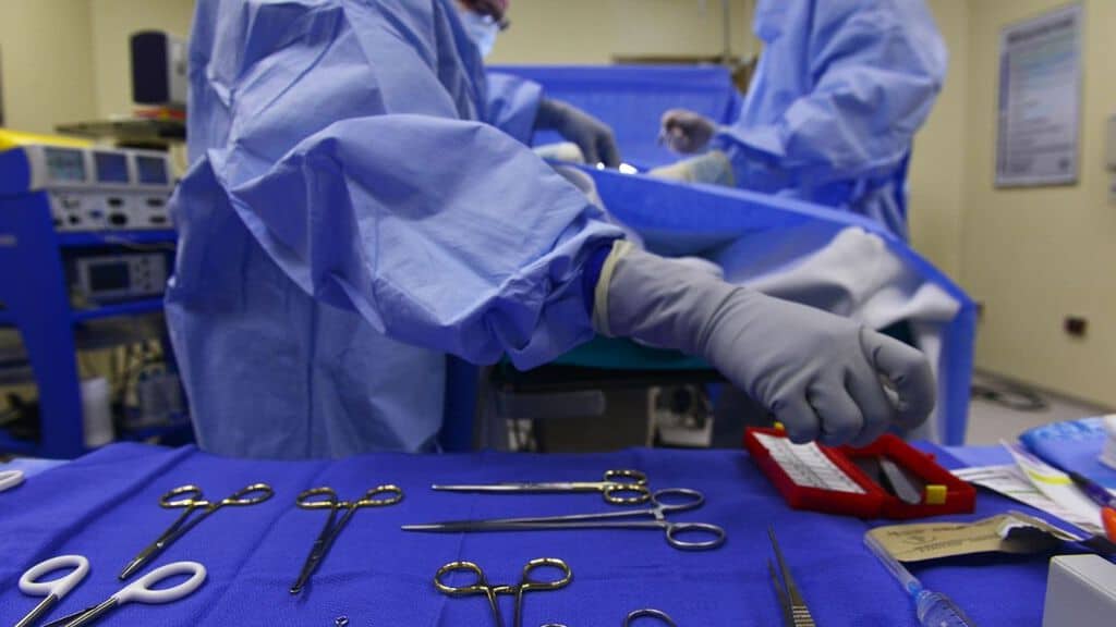 mani di un chirurgo che afferrano un bisturi in sala operatoria