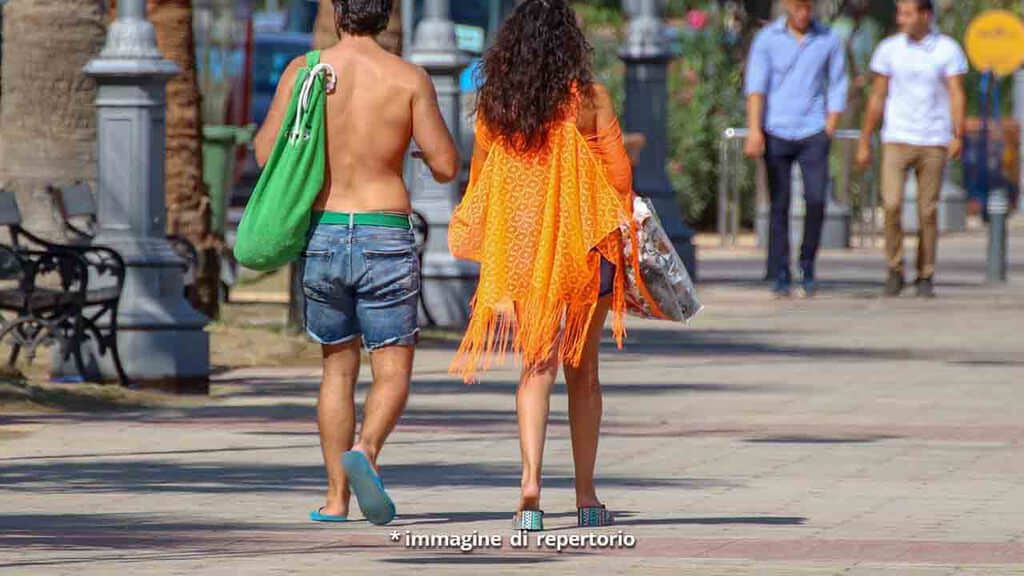 Coppia di spalle che passeggia in città tra la gente