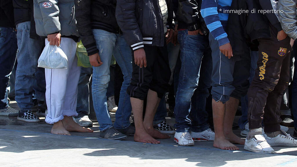 gambe di migranti in fila