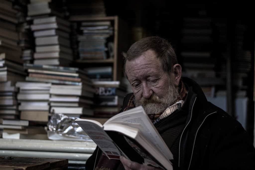 Un uomo anziano legge un libro in solitudine.