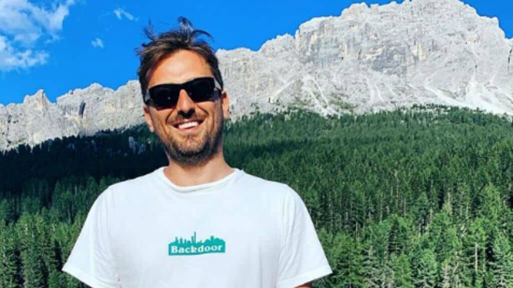 cesare cremonini a mezzo busto sorridente con dietro le montagne