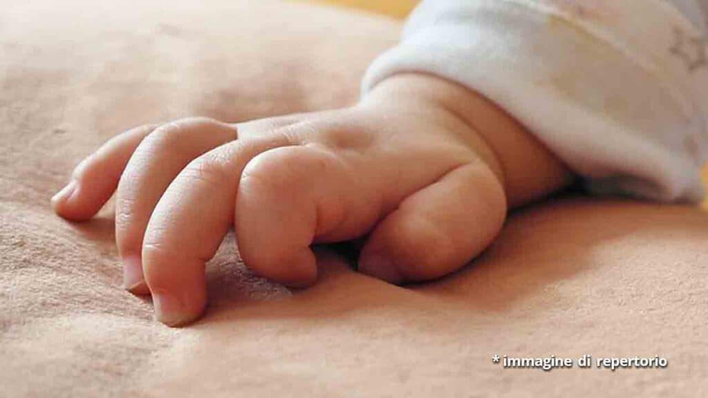 mano di un neonato sul letto