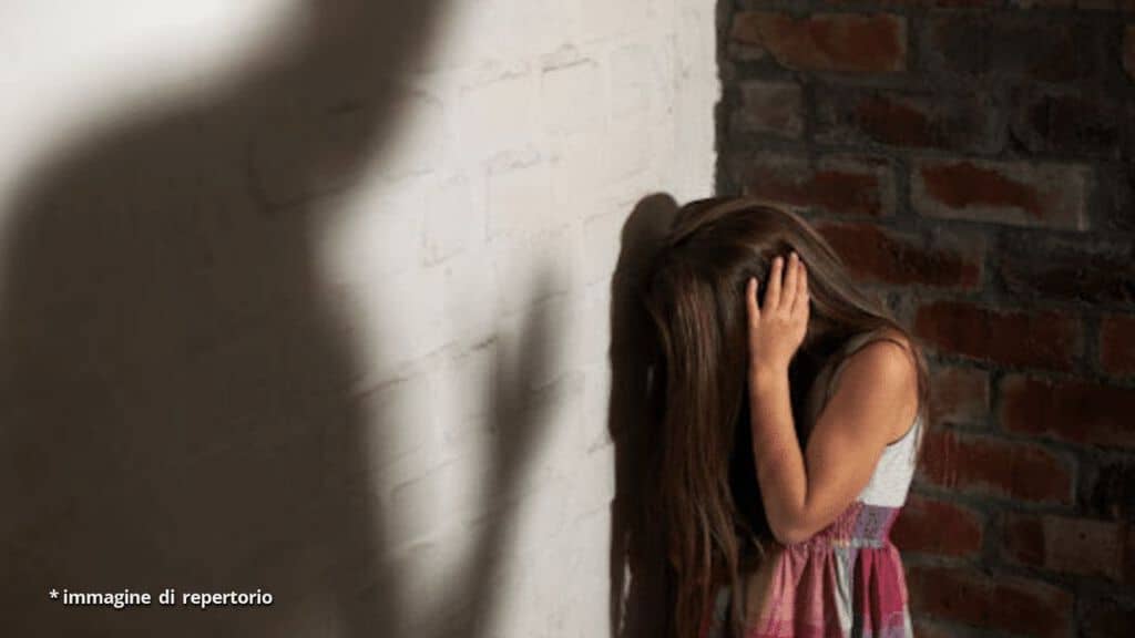 bambina con la faccia rivolta verso il muro e le mani sulle orecchie in segno di disperazione