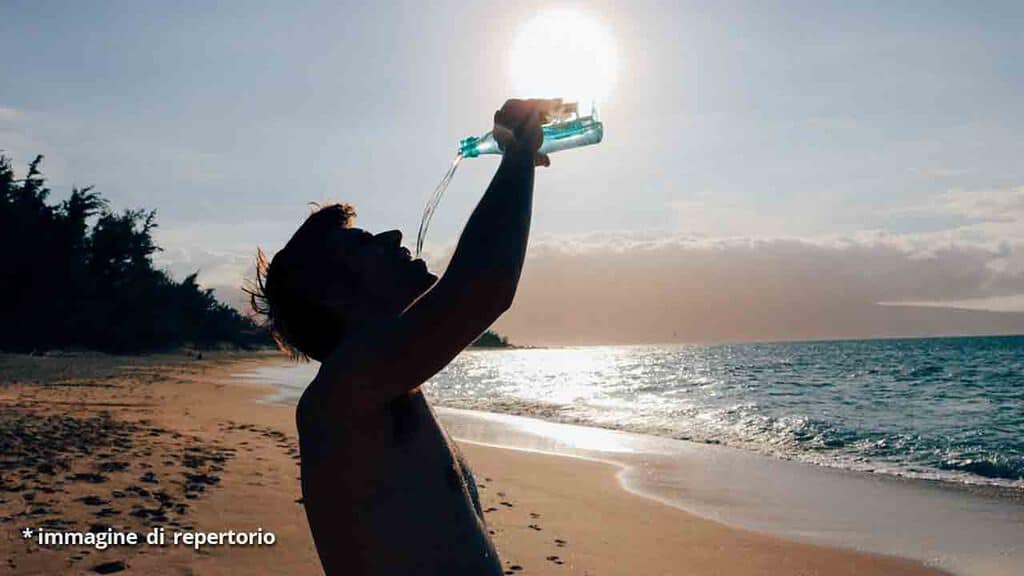 uomo beve in spiaggia