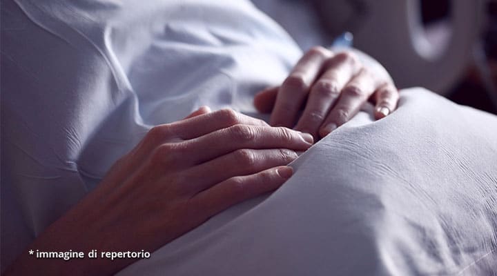 mani di donna sul letto di ospedale