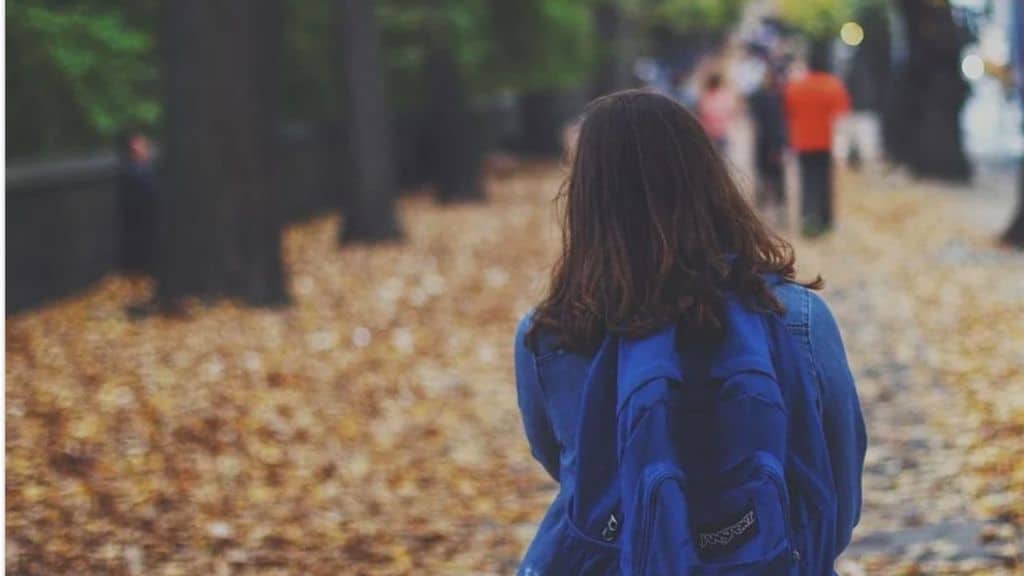 Bambina che cammina con lo zaino in spalla