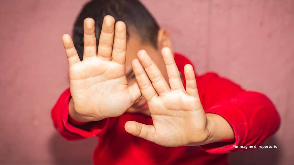 bambino che si copre il volto con le mani