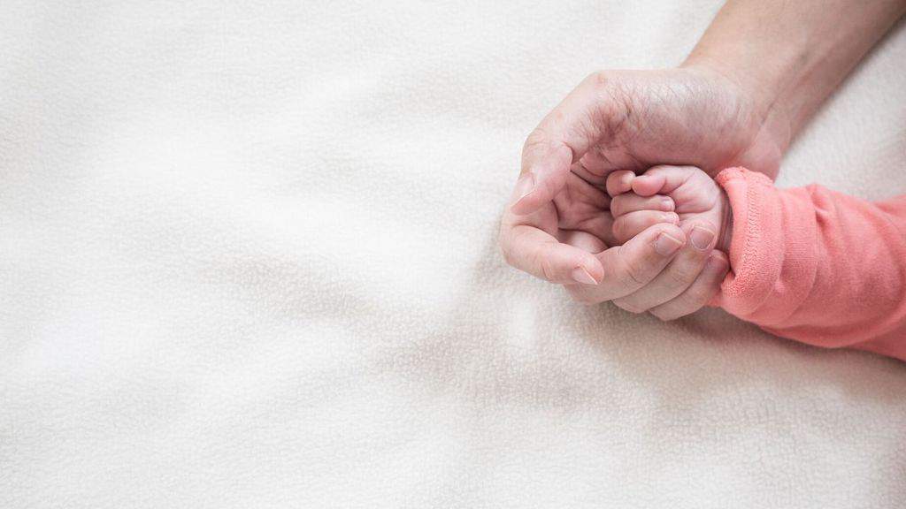 mano di una neonata in quella della mamma
