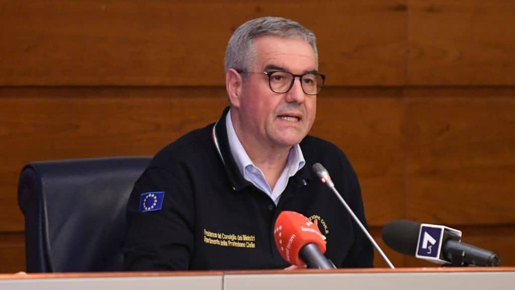 angelo borrelli, mezzo busto, seduto davanti ai microfoni dei giornalisti