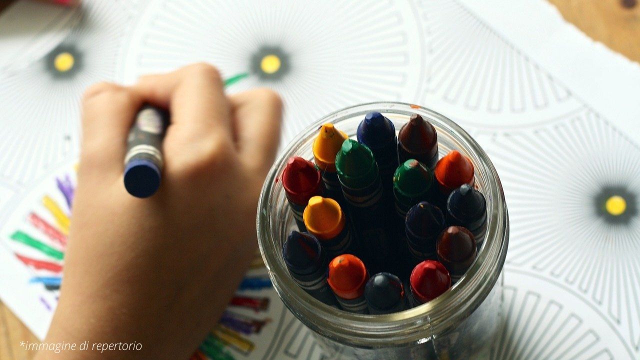 Mano di un bambino che colora con i pastelli