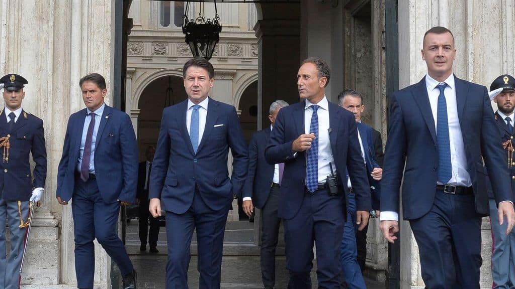 Giuseppe Conte che cammina in strada con la scorta