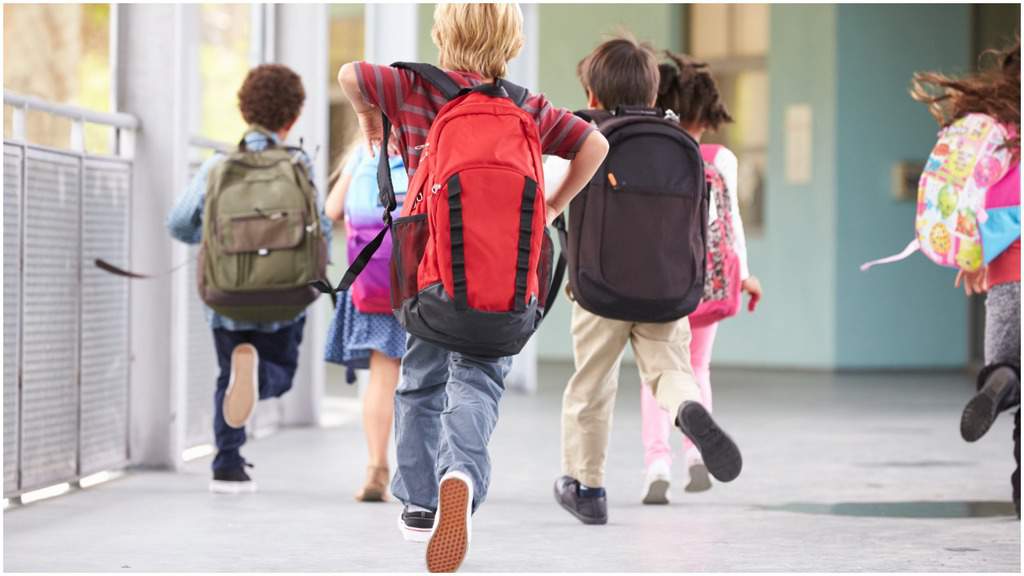 bambini con lo zaino di spalle che corrono verso la scuola