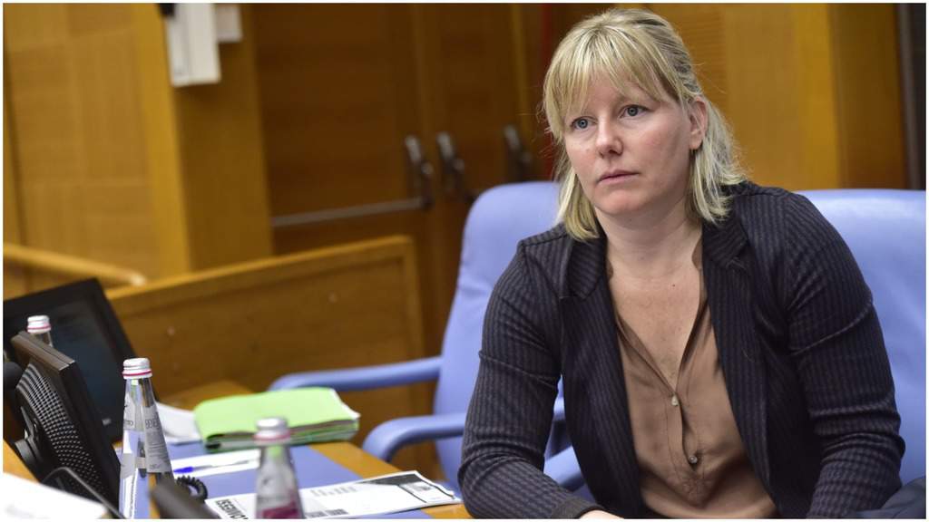 Sara Cunial, mezzo busto, seduta alla scrivania di tre quarti, davanti al monitor e ad alcune pratiche. Sulla scrivania sono presenti anche alcune bottiglie d'acqua