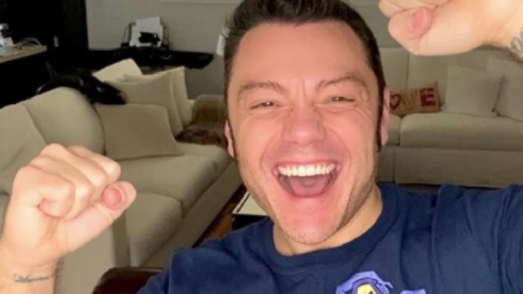 Tiziano Ferro, sorridente in casa, con i pugni stretti ealzati