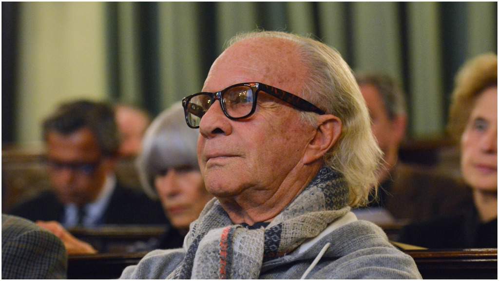 Bob Krieger, con gli occhiali, seduto in una platea con una sciarpa al collo