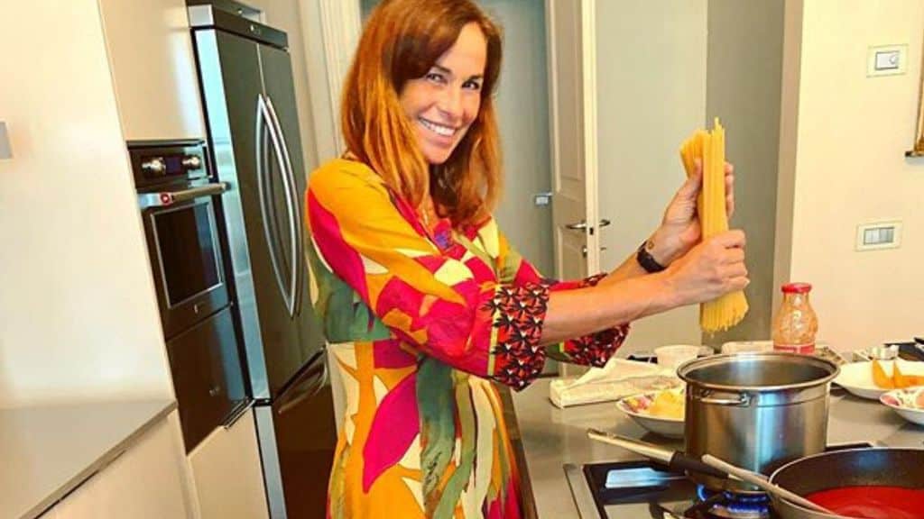 Cristina Parodi nella sua cucina con degli spaghetti in mano sospesi sopra la pentola