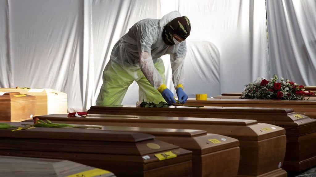 Un soldato con mascherina sulle bare dei morti da Coronavirus