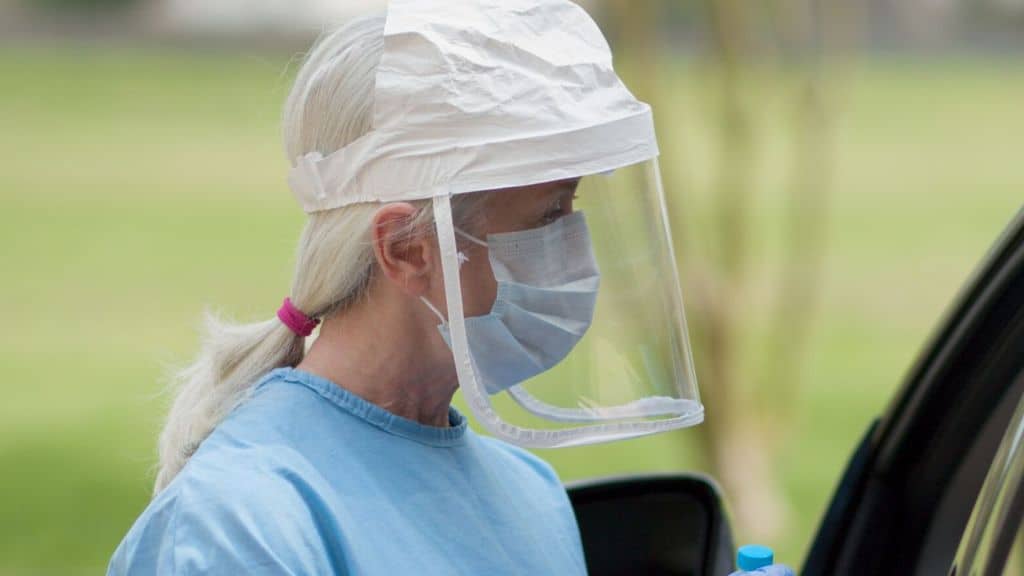 foto di una donna con visiera protettiva e mascherina