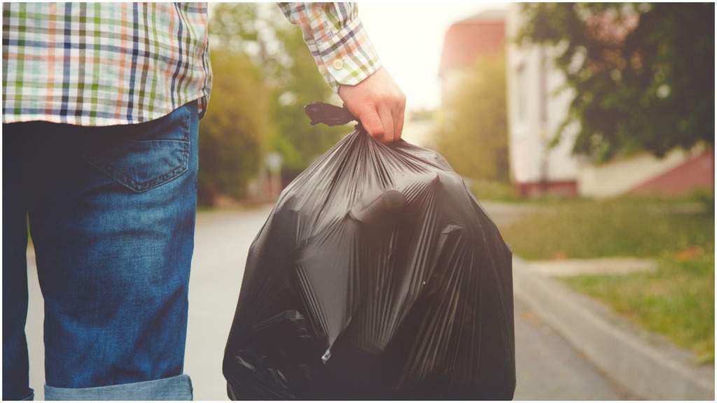 uomo con in mano un sacco della spazzatura