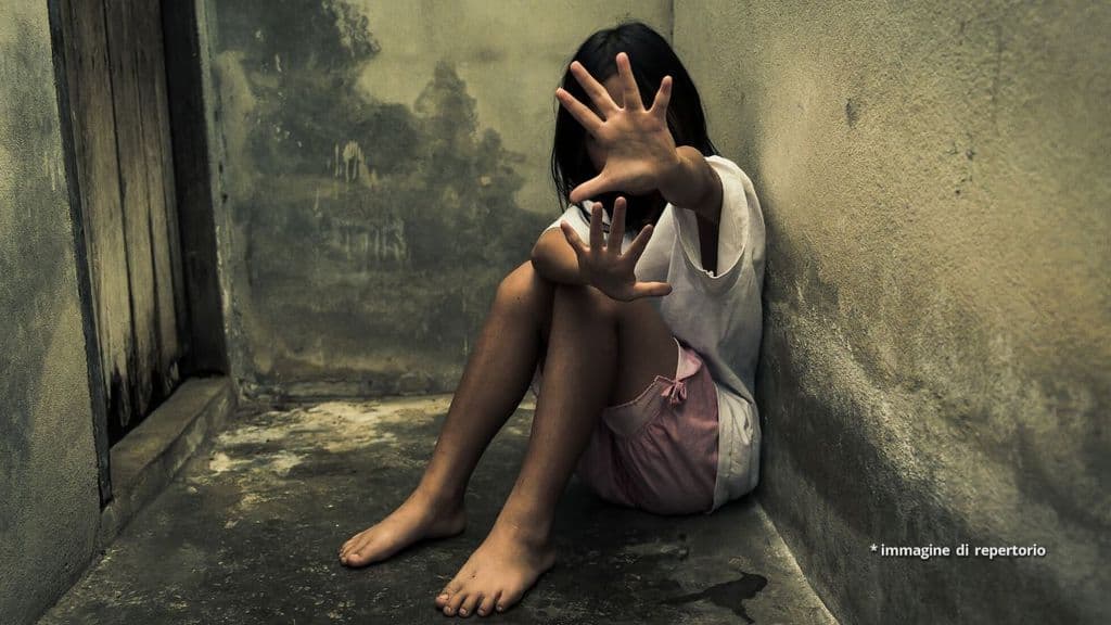 Una bambina seduta a terra nello sporco
