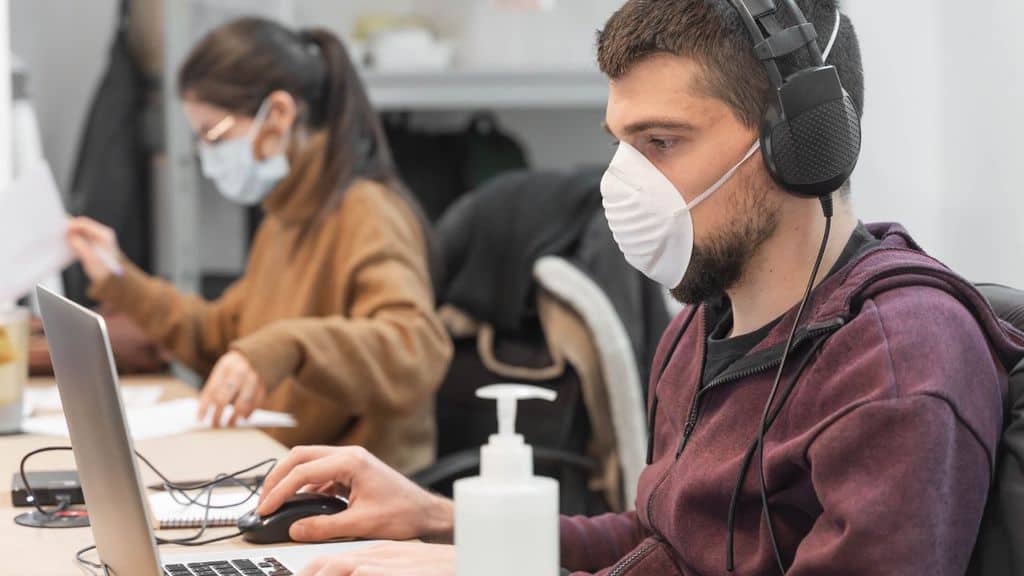 Impiegato al lavoro con mascherina per il Coronavirus