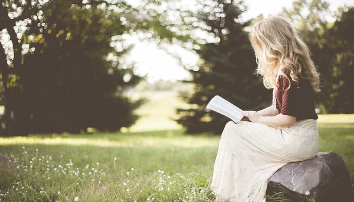 ragazza che legge un libro in un prato