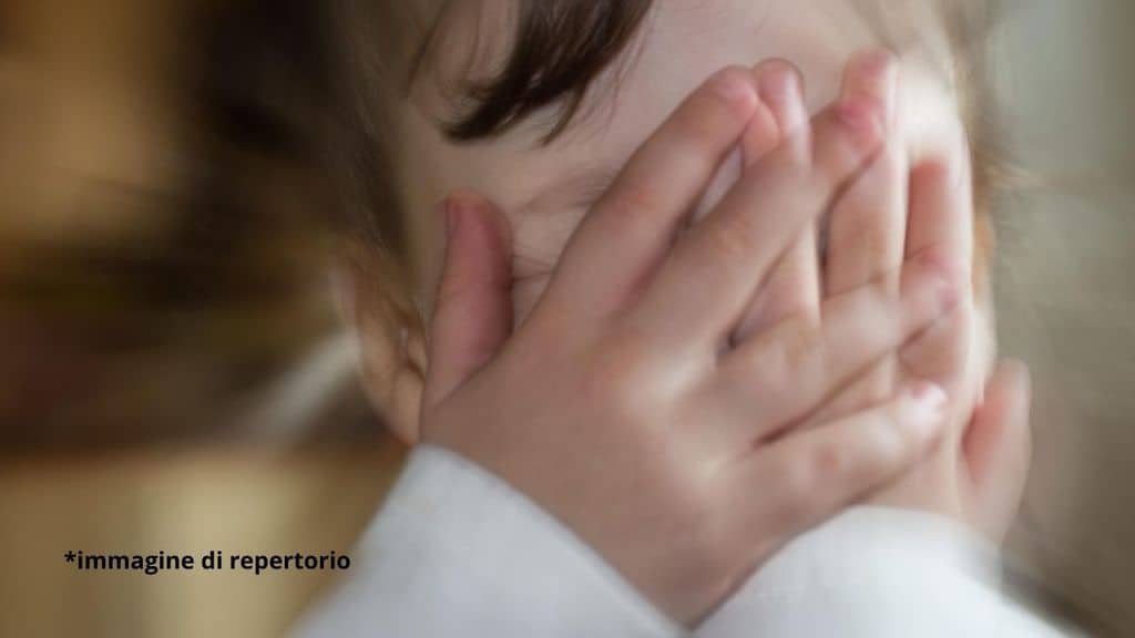 bambino che si tiene il viso con le mani