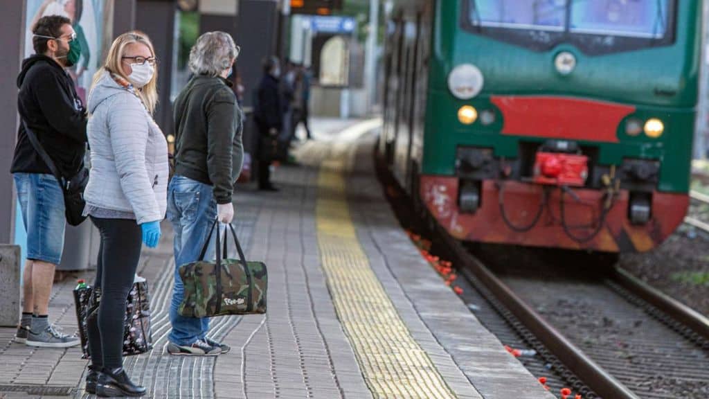 persone prendono il treno con le mascherine