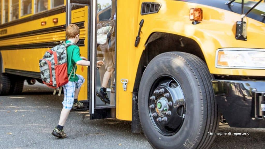 Un bambino sta salendo sullo scuolabus