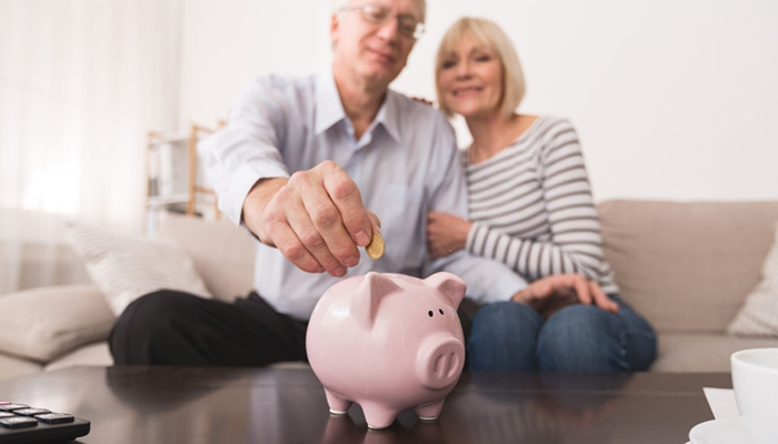 pensionati versano moneta in salvadanaio