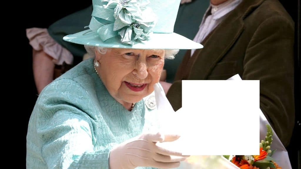 La regina Elisabetta II in primo piano con indosso un vestito turchese