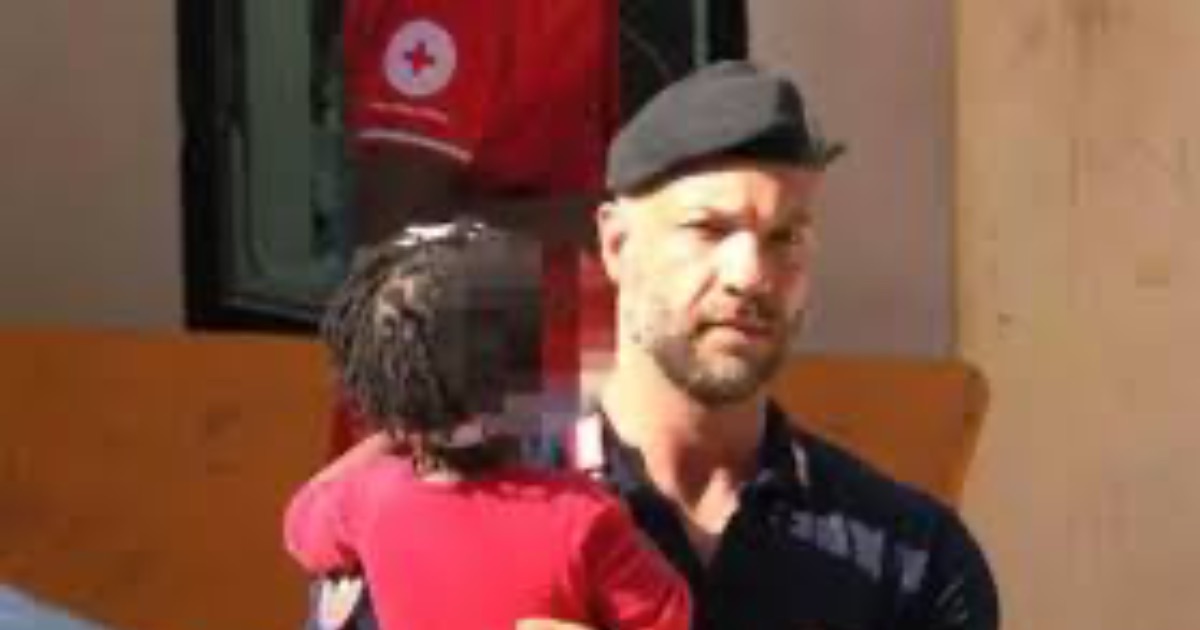 Lampedusa al collasso: un carabiniere tiene in braccio una bambina che aspetta la mamma